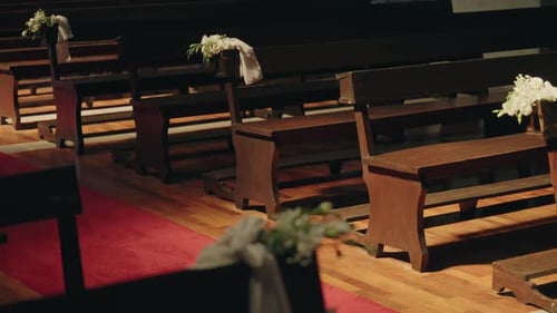 church pews with floral decorations along red carpet aisle