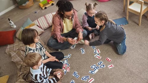 Young Male Kindergarten Educator Teaching Alphabet to Children in Classroom