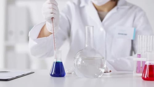 Scientist using pipette and flask in laboratory
