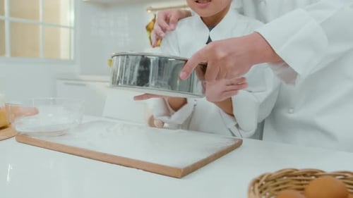 Child and Adult Sifting Flour in Bright Kitchen