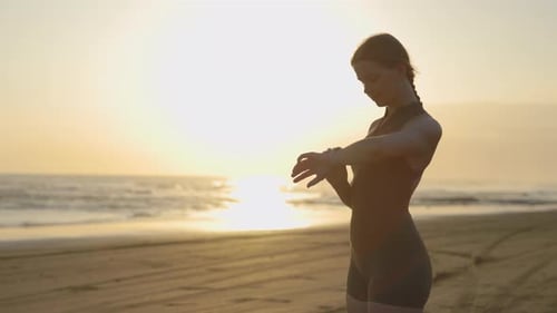 Junge Läuferin steht am Meer und schaut sich Smartwatch an Sportlerin nutzt Fitness-Tracker-Check