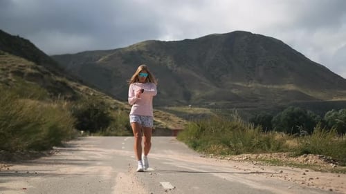Eine fokussierte Frau passt ihren Tracker an und bereitet sich auf ihr Training unter Wolken vor
