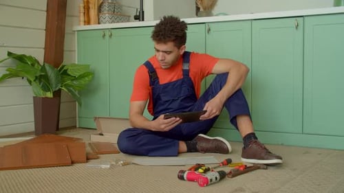 Black Handyman con tableta viendo un Vídeo tutorial para ensamblar muebles