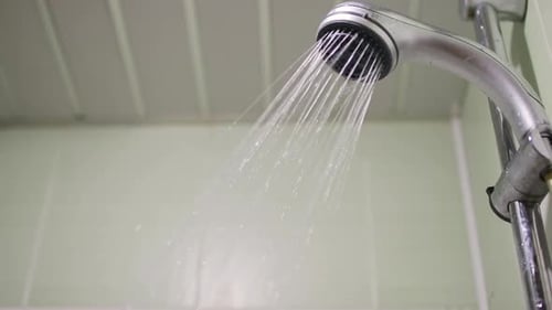 Bathroom Water Flowing From the Modern Silver Shower Head Falling Drops in Slow Motion