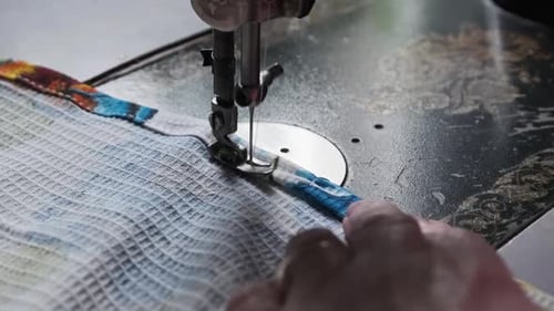 Eine alte Näherin näht zu Hause an einer Vintage-Nähmaschine