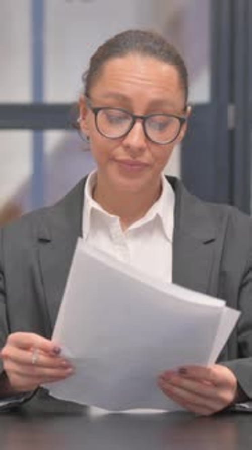 Mujer de negocios mestiza trabajando en documentos en la oficina, vídeo vertical