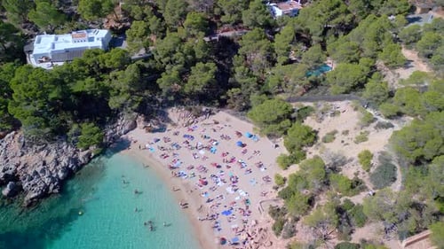 Popular dream beach for locals and tourists. Amazing aerial view flight tilt up drone
of Ibiza cala
