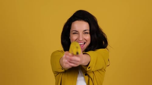 Woman Dancing with a Banana on Yellow Backdrop