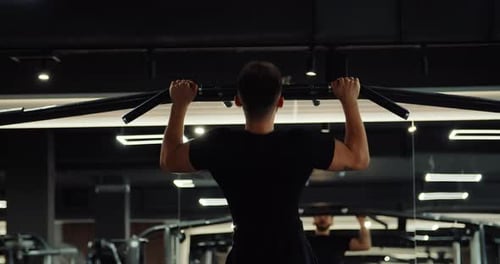 Back View Muscular Man Doing Wide Grip Pull Ups on Horizontal Bar Powerful Athlete Pumping Arm