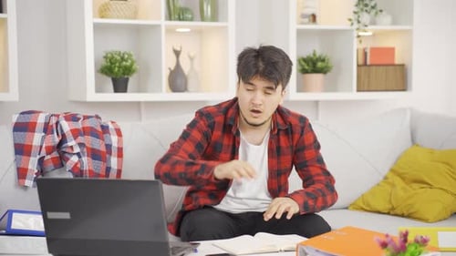 Young Man Writes in Notebook on Couch