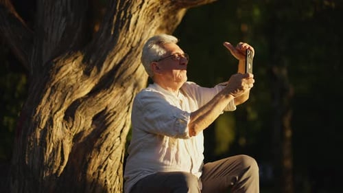 Elderly Man Taking Photo with Smartphone in Park Senior Man Using Smartphone to Take Photo