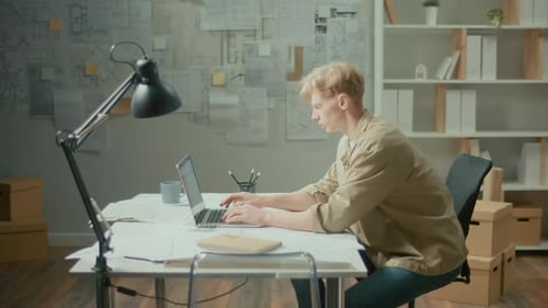 Side ViewYoung Concentrated Manager Working on Laptop in Modern Office