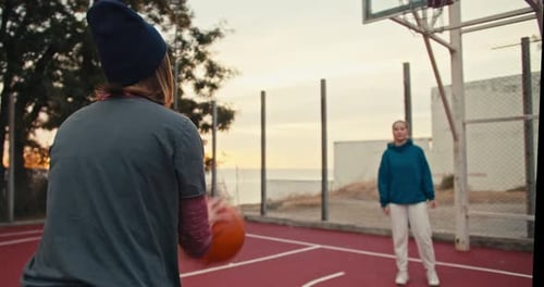 Shot From Behind a Blonde Girl with a Bob Hairstyle Receives a Basketball Catches It and Throws It