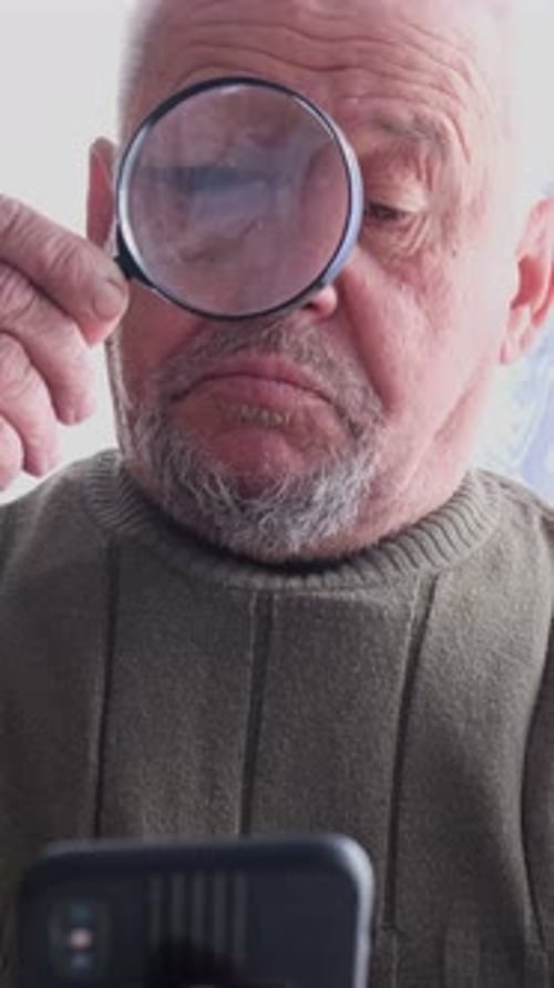 Senior Adult Uses Magnifying Glass With Phone