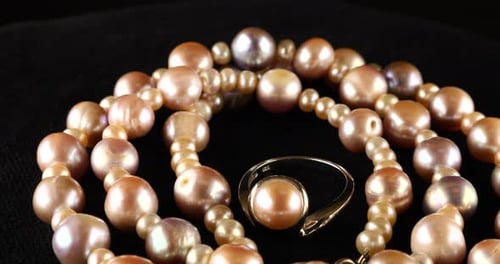 Necklace and silver ring made of natural sea pearls on black velvet.