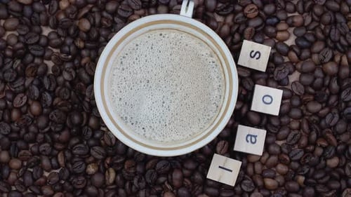 Top View of a Cup of Coffee on a Background of Coffee Beans with the Inscription Laos