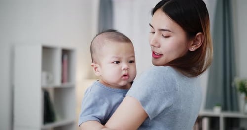 Woman Holds Baby in Brightly Lit Home