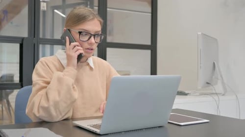 Woman Talking on Cellphone While Using Laptop