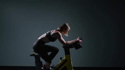 Sporty Woman is Engaged in a Modern Exercise Bike Performs Aerobic Endurance Training on the