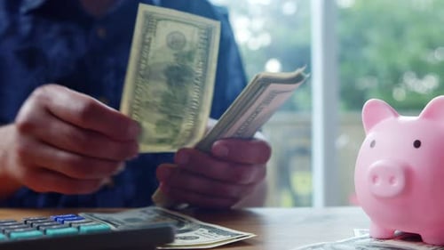 Close Up Of Hands Counting Cash In 100 Dollar Bills On A Kitchen Table At Noon