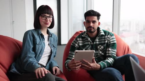 Coworkers Reading on Tablet and Laptop Screens in Office