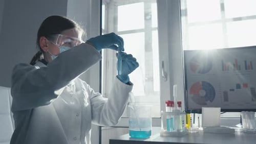 Female Scientist Conducts Experiment in Bright Lab