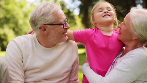 Happy Grandparents Hugging Granddaughter in Sunny Green Park