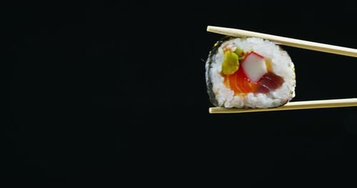 Sushi Roll held with Chopsticks Close Up
