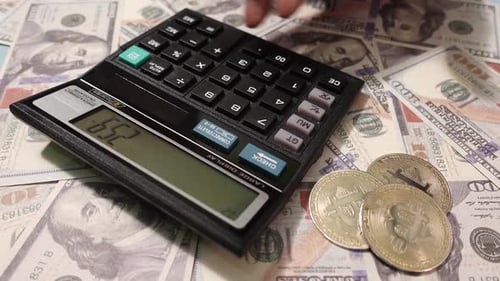 Fingers Using Calculator on Money and Bitcoin