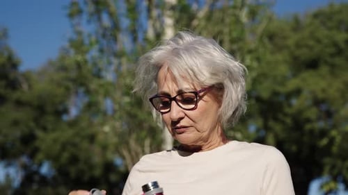 Senior Woman Drinking Water After Exercising Outdoors Slow Motion