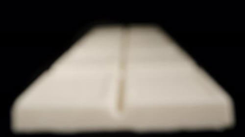 A white chocolate bar on a black background, slowly focusing into the distance using a focusing tech
