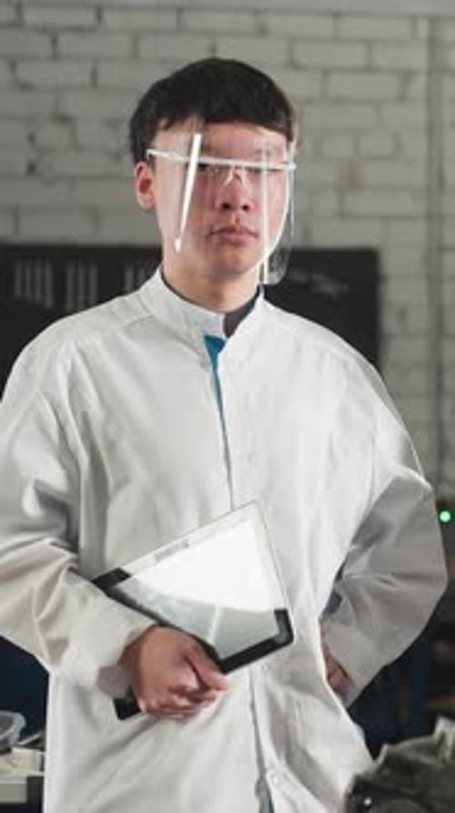Two Focused Students Standing Near Engine in Mechanical Workshop Holding Tablets