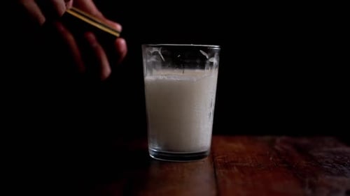 Candle being Lit in Glass on Wooden Surface