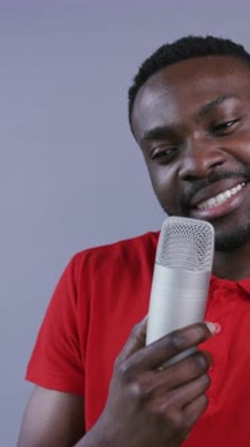 Smiling Young Adult Talks Into a Microphone