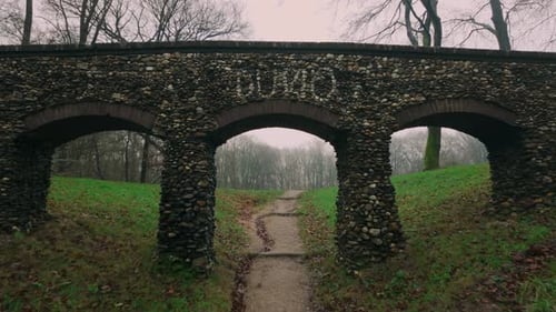 Nahaufnahme der Steinbogenbrücke mit Pfad und Grün