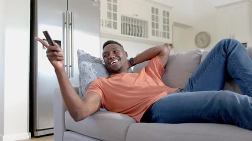Young Man Relaxing on Sofa and Watching TV at Home
