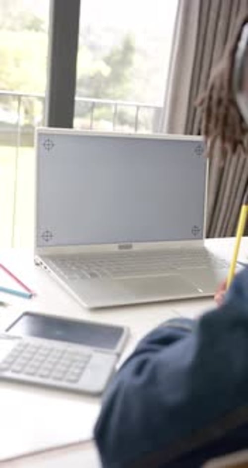 Vertical video of african american boy using laptop with copy space on screen at home, slow motion