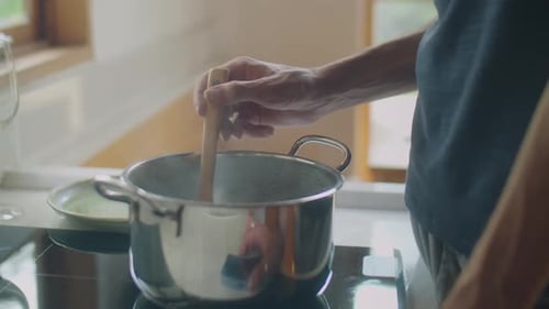 Person Stirring a Pot on the Stove