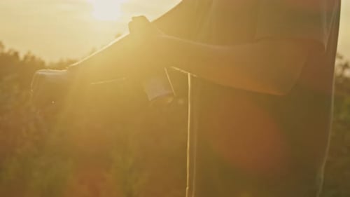 Man Using Mosquito Repellent Spray on Mountain at Sunset