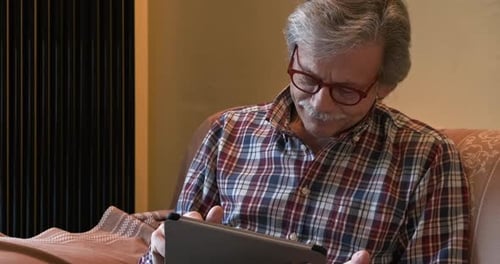 Senior Man Using Tablet on Couch Indoors