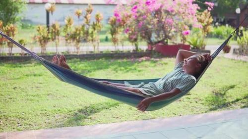 Woman is resting in hammock and enjoying summer in garden