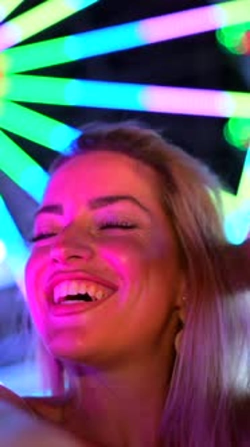Smiling Woman Posing in Front of Neon Lights