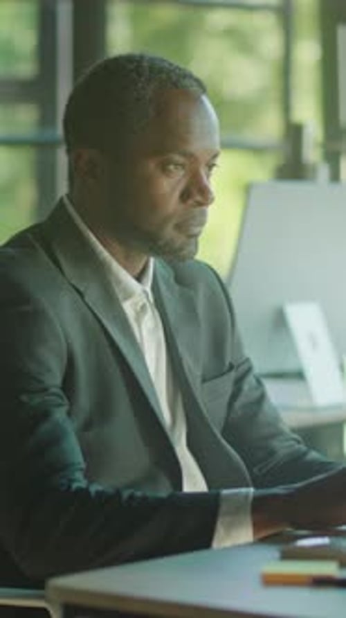 Man in Suit Works at Desk and Looks Up