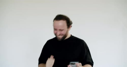 Man Cheers While Looking at His Phone