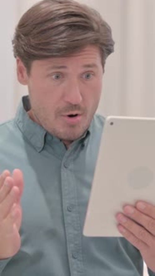 Man Looking at Tablet with Surprised Expression