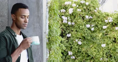 Man Drinking Coffee Outdoors with Flowers