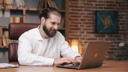 Bearded Man Working on Laptop at Desk