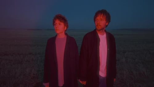 Couple Holding Hands in Open Field with Red Illumination at Night