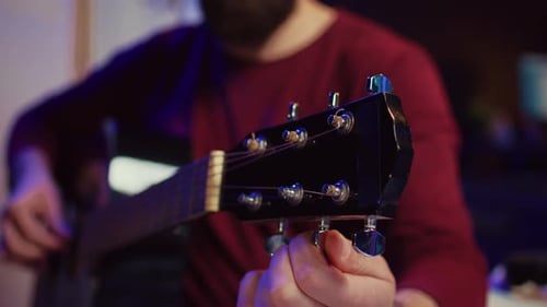 Intérprete musical afinando su guitarra girando las perillas