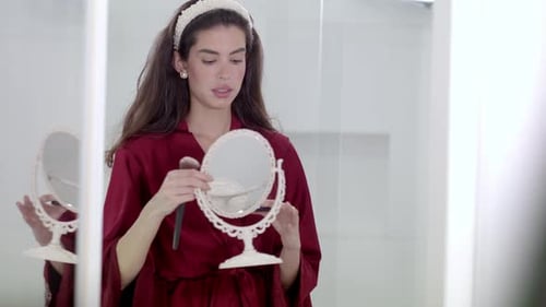 Elegant Woman Applies Makeup in Bright Bathroom